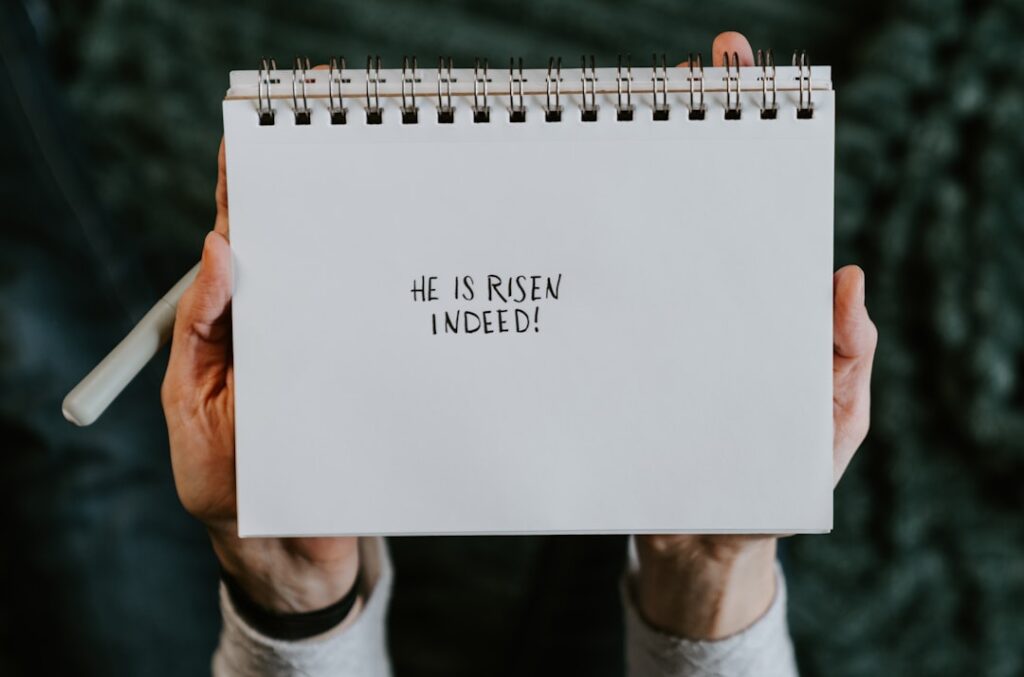 Hands holding a notebook with 'he is risen indeed!'